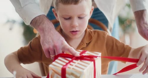 Little Boy Unwrapping Present with Help from Adult
