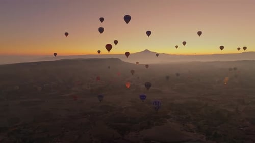 Drone view of hundreds of colorful hot air balloons soaring at sunrise in Cappadocia