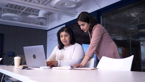 Two women collaborate at a modern workplace setting