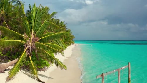 Paradise White Sand Beach Turquoise Ocean Green Palm Trees and Blue Sky with Clouds on a Sunny Day