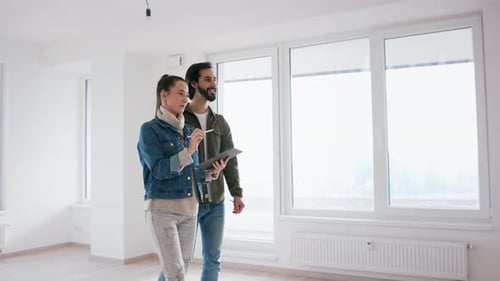 Couple in Empty Apartment Discussing Plans on Tablet