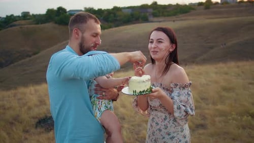 Happy Family with Baby Celebrate First Year Eat Cake in Field at Sunset Autumn and Lifestyle