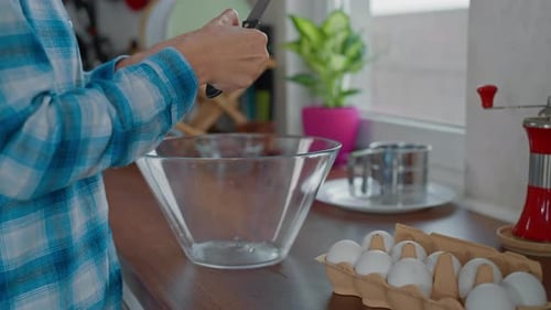 Person Cracking Eggs in a Kitchen with Knife