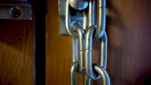 Close-Up Of Door Chain And Lock On Wooden Door For Security And Access