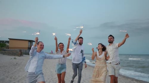 Friends Celebrating with Sparklers on a Beach at Dusk