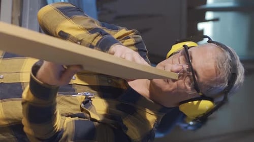 Woodworker Inspecting Plank in Workshop