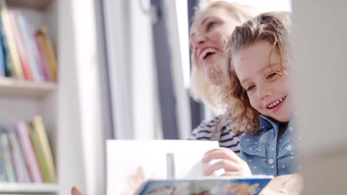 Mother and Daughter Reading a Book Together Indoors