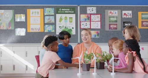 In school, female teacher and students discussing wind turbines and plants in classroom
