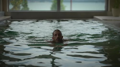 A Swimmer Relishes the Calm of an Indoor Pool with a Beautiful View of Nature Outside
