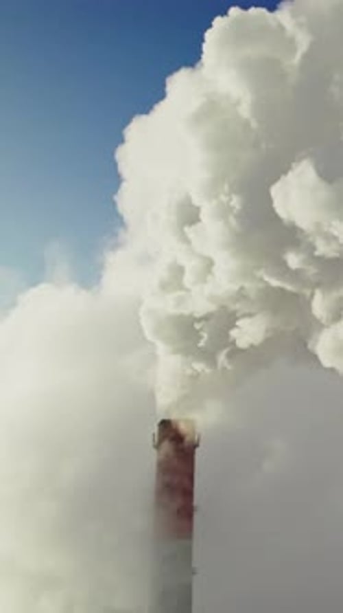 Smokestack Billowing Smoke Against Blue Sky