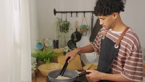 Young adult cooking inside white kitchen