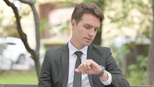 Man in Suit Checking Watch on Park Bench