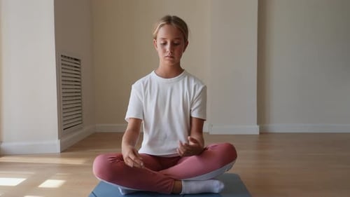 Front View of Little Calm Girl Relaxing in Lotus Position with Folded in Mudra Gesture Hands and