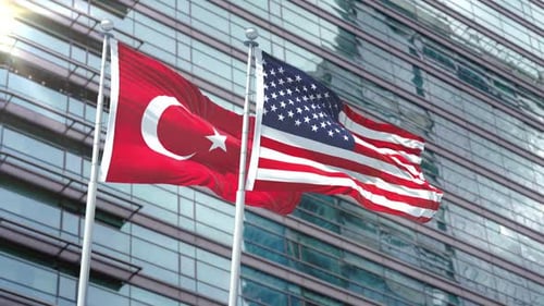 Waving Turkish and American Flags in Front of Modern Building
