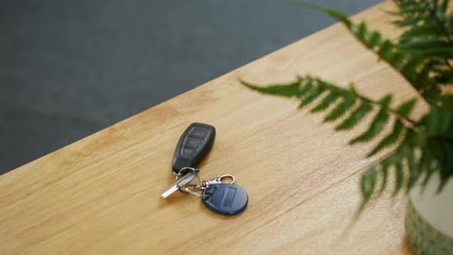 Picking up keys on a table. A man grabs his car keys as he leaves the office