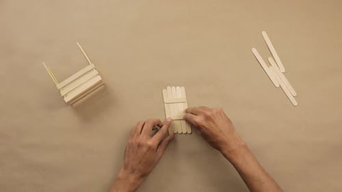 Hands Crafting Wood Structure with Glue