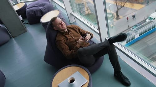 Man Relaxing in Beanbag Chair with Phone