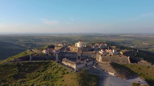 Aerial view of fortified village on hill.