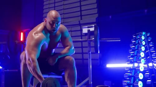 Muscular Man Bicep Curls in Brightly Lit Gym