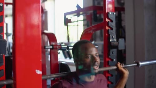 African American Bodybuilder Doing Squats Using a Barbell in a Gym to Train His Legs and Back