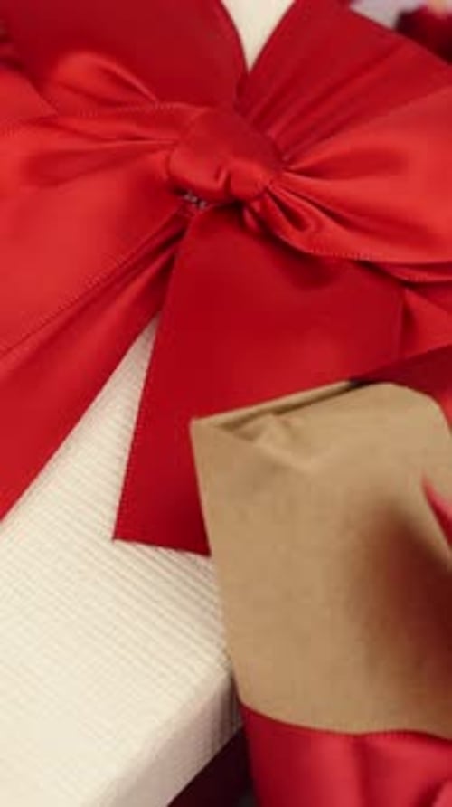 Close up of rotating Valentine Day gifts with red ribbon bows. Vertical video