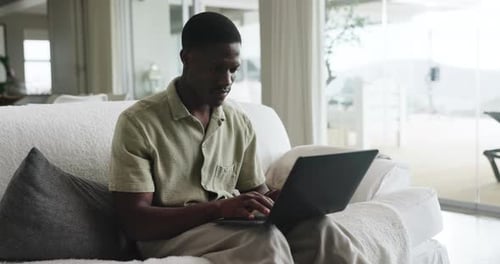 Man Working On Laptop on Couch Indoors