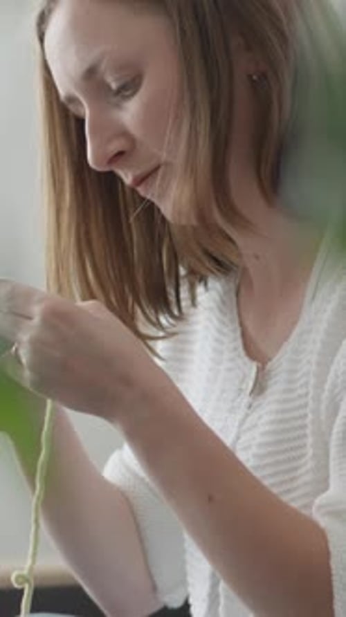 Woman Crafting Intricately with Light Green Yarn