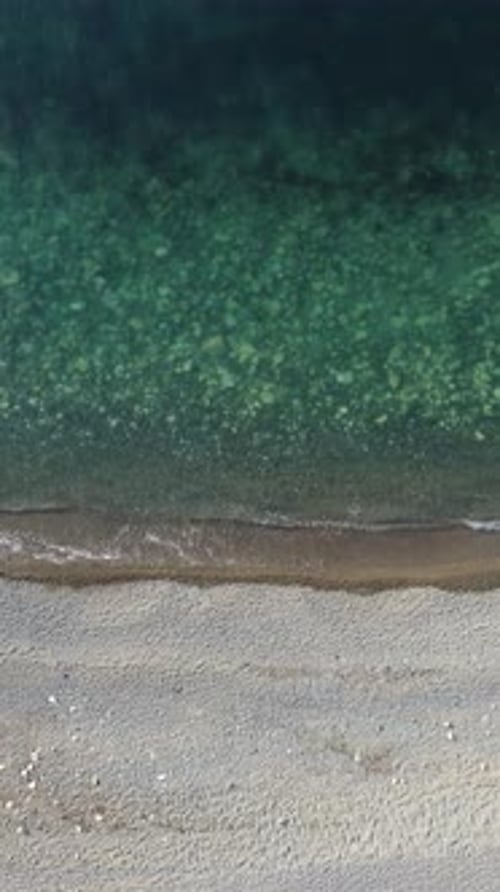 Aerial Vertical View of Beach with Wave Caressing Shore Sun Glare Small Waves on the Water Surface