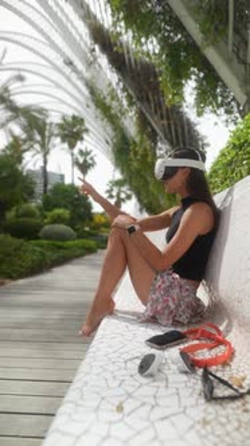 A Woman is Enjoying the Experience of Using a VR Headset in a Futuristic Garden Setting