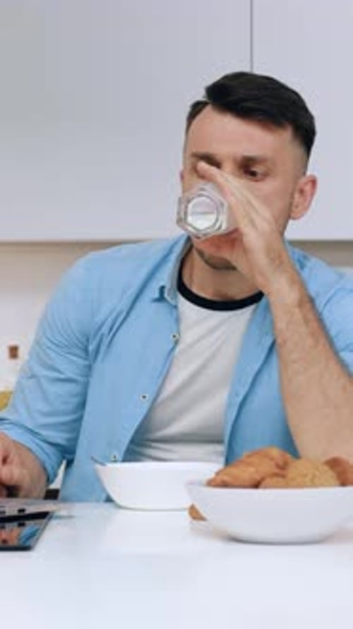 Attractive Serious 35Aged Guy Enjoying Fresh Milk and Attantivly Watch on Laptop Screen to Search