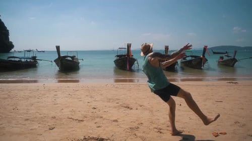 Very muscular white man does a back flip on the beautiful sandy beach of the Thai island of Krabi wh