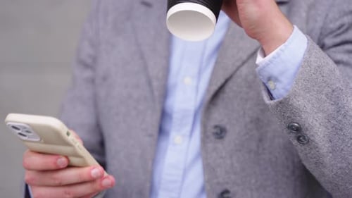 Young Adult Man Uses Phone and Drinks Coffee