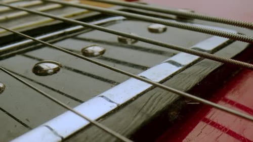 Primer plano de cuerdas de metal estiradas sobre la pastilla de la guitarra