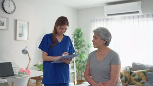 Asian caregiver explain diagnosis to senior woman at nursing home care.