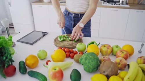 Woman Cutting Green Pepper in Bright Kitchen