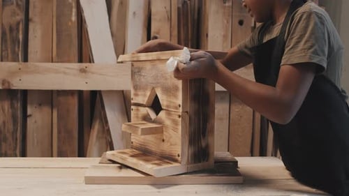 Un enfant préadolescent termine la fabrication d'un nichoir à oiseaux fait main en studio