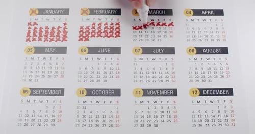Hand Marking Calendar Dates with Red Crosses for March and April