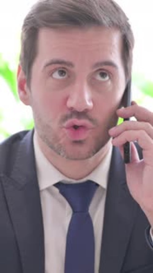 Angry Young Businessman Talking on Phone in Office, vertical video