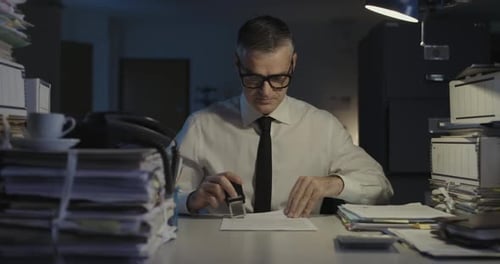 Businessman Stamping Documents in Office at Night