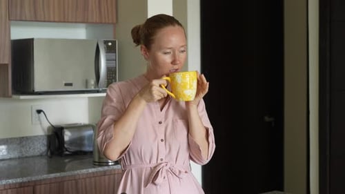 Woman Sips Coffee in Modern Kitchen