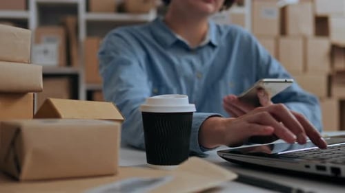 Woman Working with Laptop and Boxes in Office