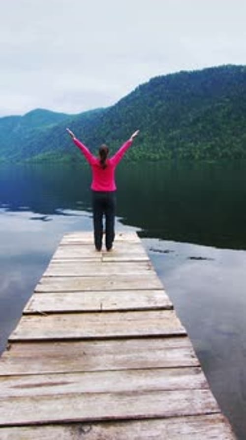 Calm Day By the Lake with a Woman Walking on a Wooden Dock in Nature