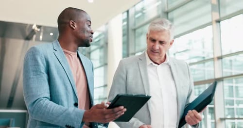 Businessmen Discussing Tablet Information in a Modern Office