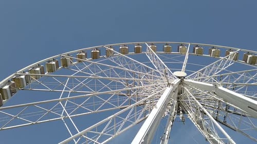 Une
grande roue blanche tourne dans un parc d'attractions.