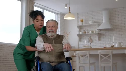 Caring Woman Assisting Senior Man in Wheelchair Exercise