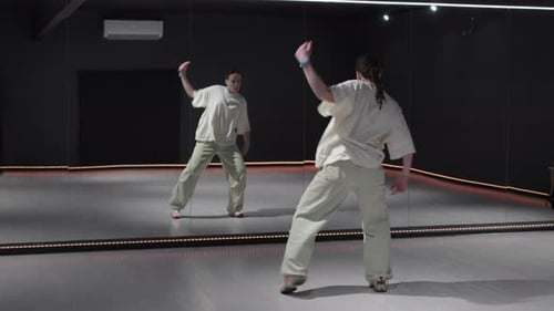 Young Woman Practices Modern Dance in Studio with Mirrors and Neon Lights