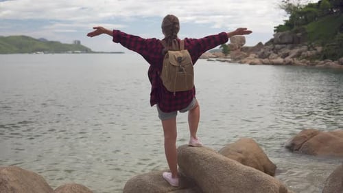 Female tourist with backpack is enjoying awesome sea view
