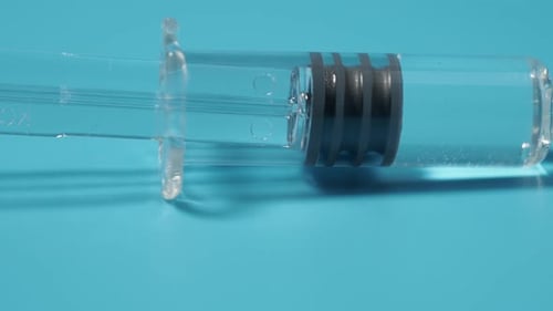Injektionsspritze mit Impfstoff auf blauem Hintergrund, Medizinkonzept.