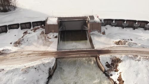 Small River Dam crossing frozen and covered by snow - Fly over aerial shot