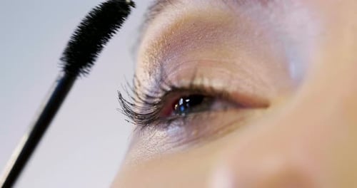 Eine Frau trägt die Wimperntusche auf die Augen auf, um das beste Make-up zu erzielen und die Farbe und das Merkmal hervorzuheben